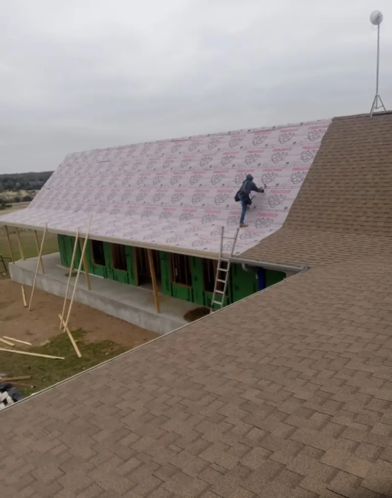 Worker preparing underlayment for a metal roof installation in Navarre